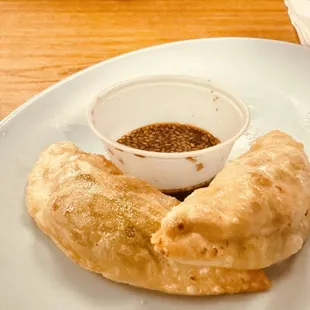 a plate of dumplings and a bowl of sauce