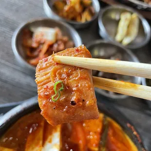 a close up of a piece of meat being lifted by chopsticks