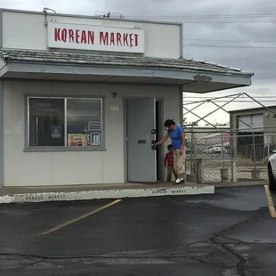 a man standing outside of a korean market