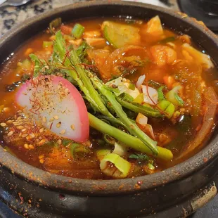 a bowl of soup with asparagus and radishes