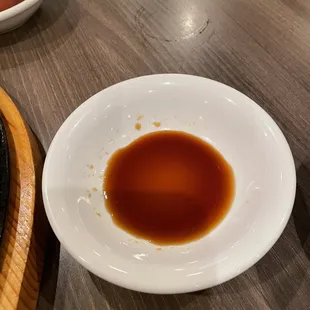 a bowl of sauce and a plate of sushi