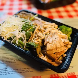 a meal in a plastic container on a checkered tablecloth