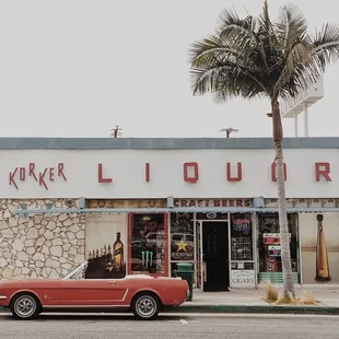 a red car parked in front of a liquor store