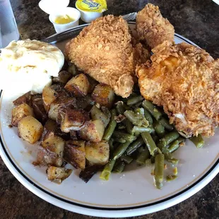 a plate of fried chicken, potatoes, green beans, and mashed potatoes