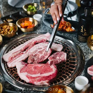 a person cutting meat on a grill