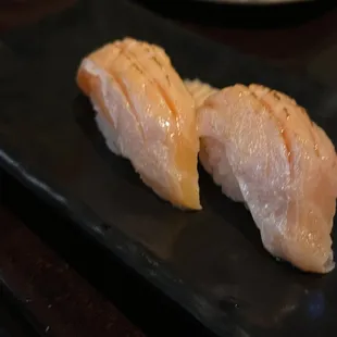 two pieces of fish on a black plate