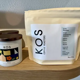 a bag of kos coffee next to a candle
