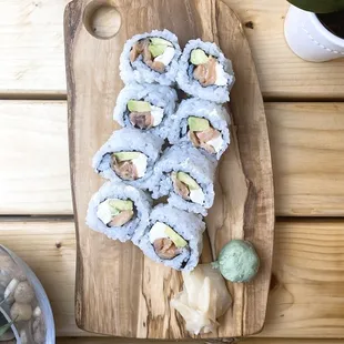 a wooden cutting board with a variety of sushi on it