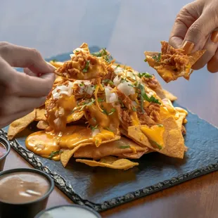 a plate of nachos with sauce and dippings