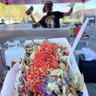 a hand holding a plate of nachos