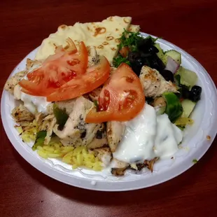 Chicken plate with salad, rice, pita, and cucumber sauce.