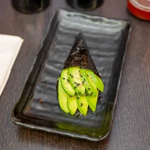 an avocado sushi on a plate with chopsticks