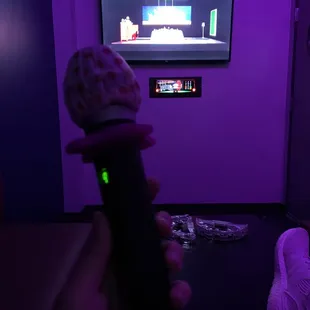 a person holding a microphone in front of a tv