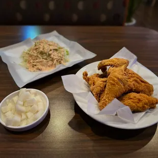 two plates of fried chicken and a bowl of coleslaw