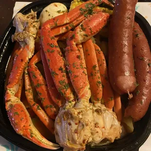 a plate of crab legs, potatoes, and a hot dog