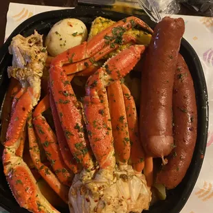 a plate of crab legs, potatoes, and a hot dog