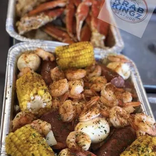 two trays of shrimp, corn, and sausage