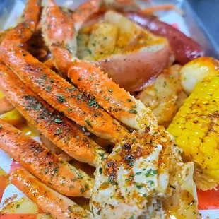 crab legs, corn, potatoes, and corn on a plate