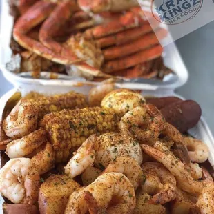 two trays of shrimp, corn and potatoes