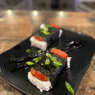two pieces of sushi on a black plate