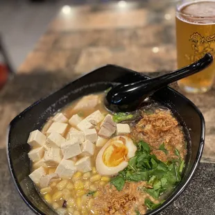 a bowl of ramen and a glass of beer