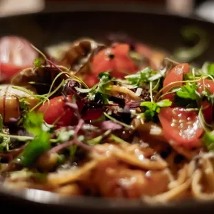 Roasted Bell Pepper Pasta garnished with shrimp, clams, prosciutto, parmesan cheese, balsamic glaze, and roasted bell pepper sauce