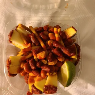 a plastic container filled with nuts and apples