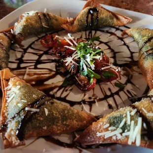 SPINACH WONTONS (6) Filled with creamy spinach topped with bruschetta and finished with a drizzle of balsamic glaze.