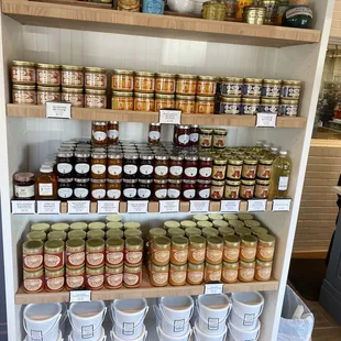 a woman standing in front of a shelf full of jars