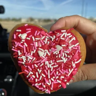 a person holding a heart shaped doughnut