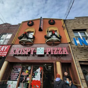 wo people walking in front of a krispy pizza restaurant
