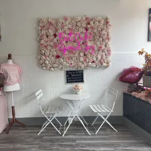 a table and chairs in front of a floral wall