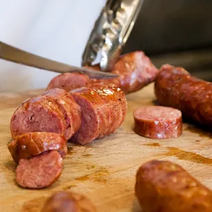 a person cutting sausage on a cutting board
