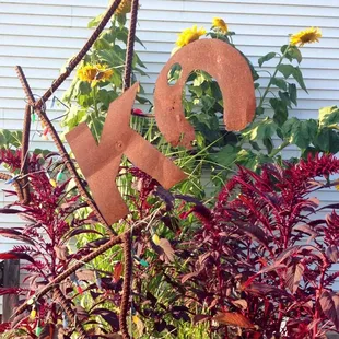 a garden with flowers and a rusted metal sign