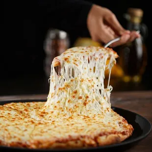 a hand holding a piece of cheese pizza