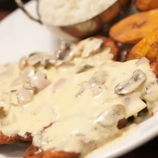 a plate of chicken with mushroom gravy and potatoes