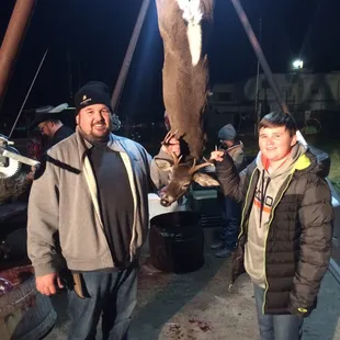 two men holding a dead deer