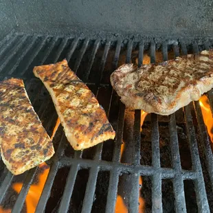 two steaks cooking on a grill