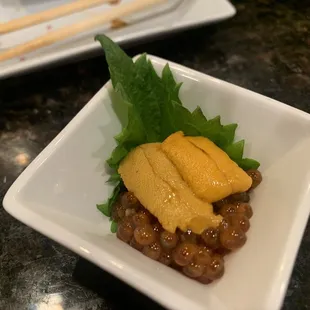 a square white plate with a salad and chopsticks