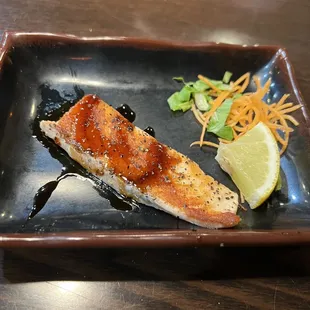a piece of salmon on a black plate