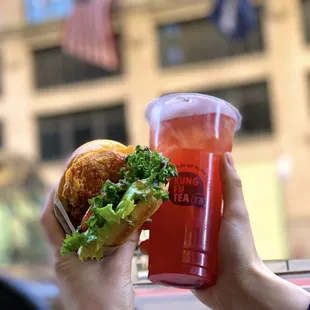 a person holding a sandwich and a drink