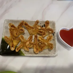 a plate of fried dumplings with dipping sauce