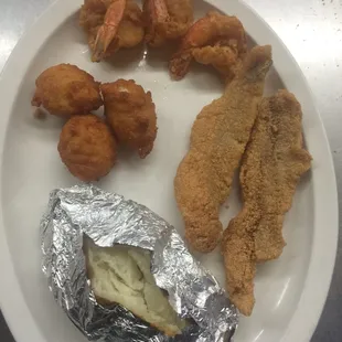 a plate of fried fish, shrimp, and potatoes
