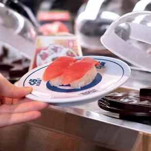 a person holding a plate of sushi