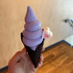 a hand holding a purple ice cream cone