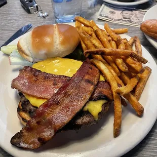 Bacon cheeseburger with lettuce, and fries.