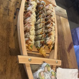 sushi boat with shaggy dog roll, passion roll, and california roll.