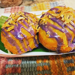 two doughnuts with purple icing on a plate