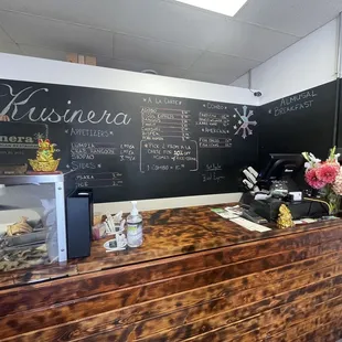 a coffee shop counter with a menu on the wall