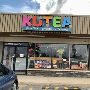 the front of a store with a car parked in front of it